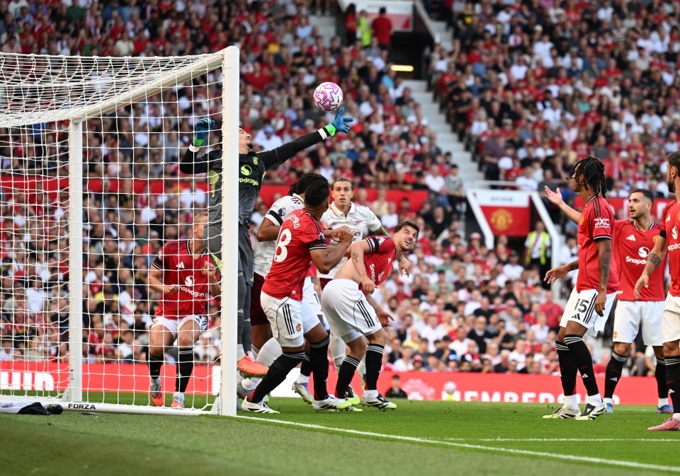 Manchester United goalkeeper Altay Bayindir jumping to stop a goal.