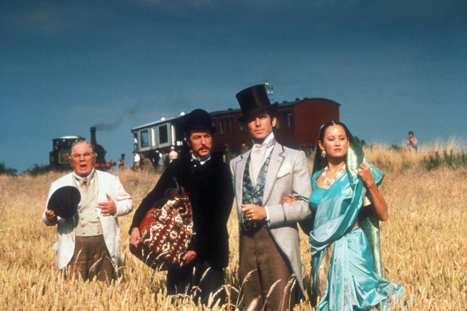 Still from *Around the World in 80 Days* featuring Peter Ustinov, Eric Idle, Pierce Brosnan, and Julia Nickson.