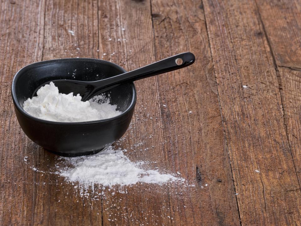 Cornflour in a black bowl with a spoon.