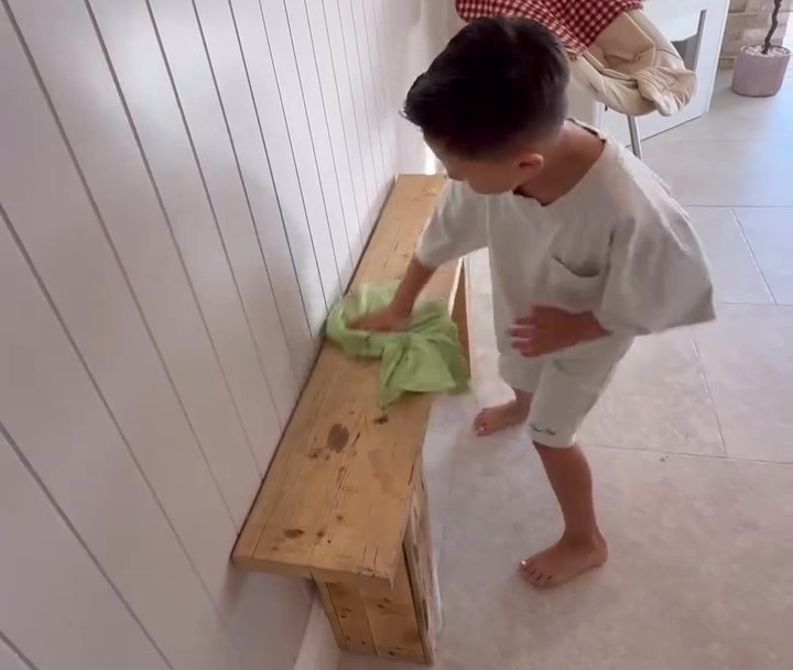Boy cleaning a wooden bench.