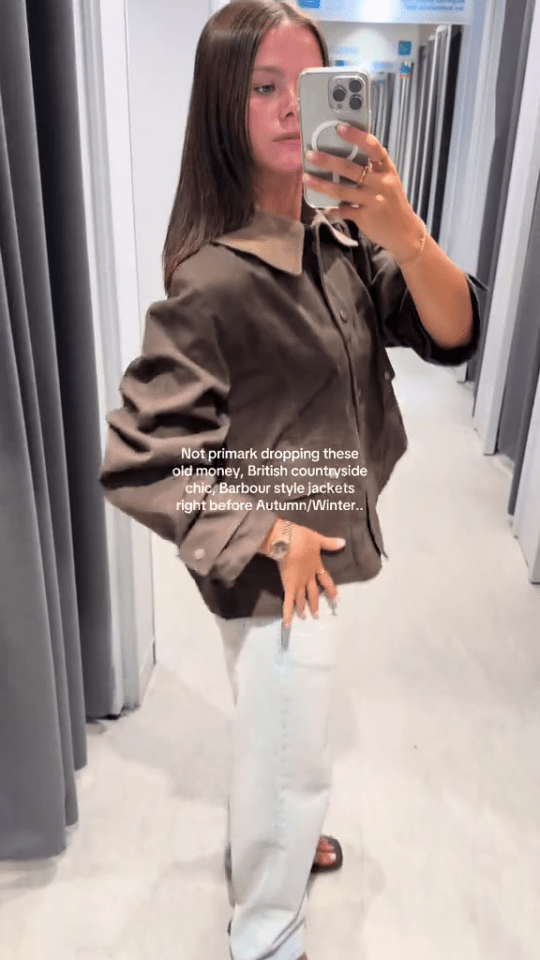 Woman in Primark trying on a Barbour-style jacket.
