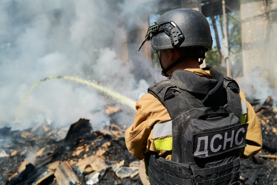 Ukrainian emergency services firefighter extinguishing a fire at a damaged warehouse.