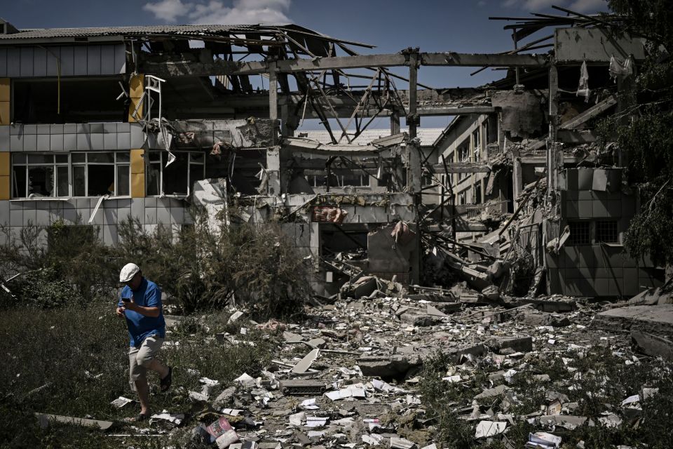 A person walks past a destroyed school in Bakhmut, Ukraine.