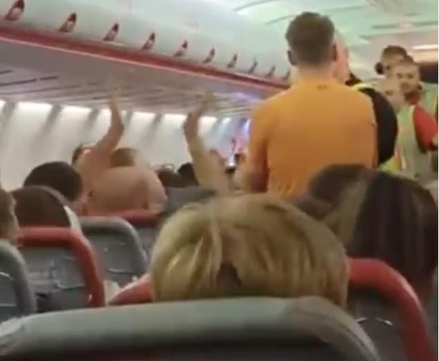 The entire flight burst into cheers and applause as the man was finally detained and escorted off of the plane, with one yelling: 'In a bit, lad!'