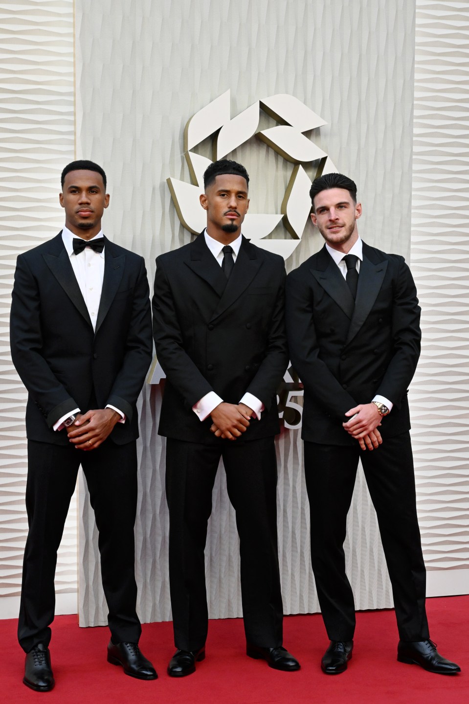 Three men in tuxedos at an awards ceremony.