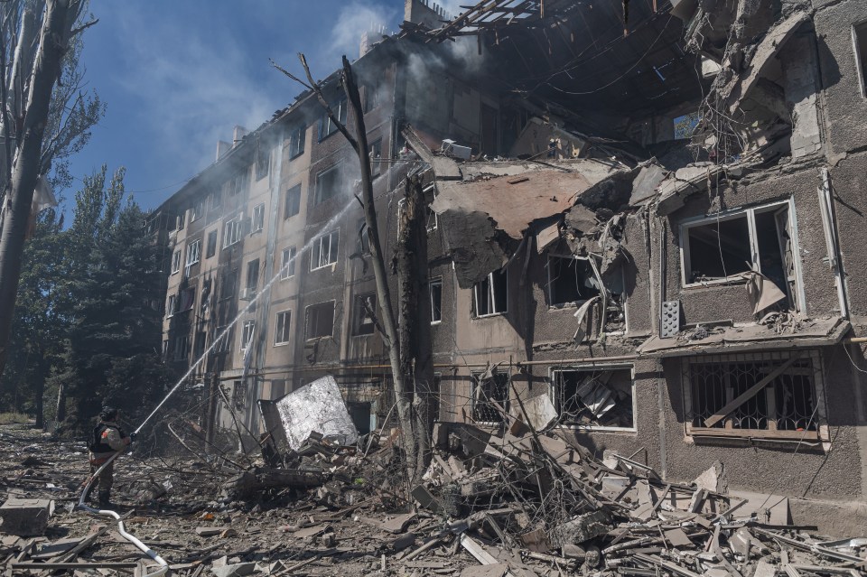 Ukrainian firefighters extinguishing a fire in a damaged residential building.