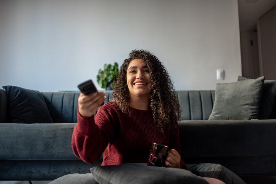 Smiling young woman watching television.