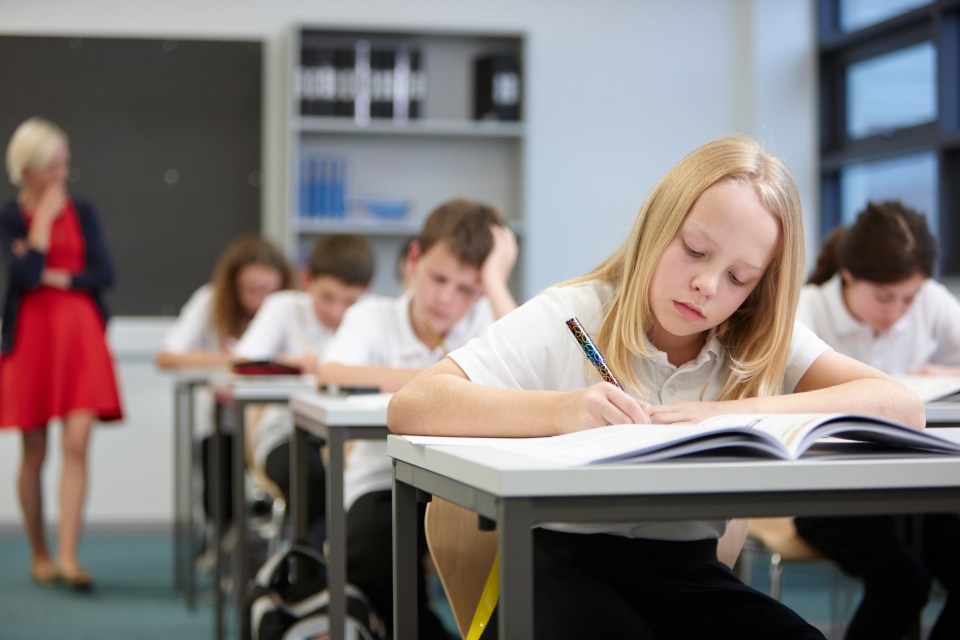Teacher observing students taking a test in a classroom.