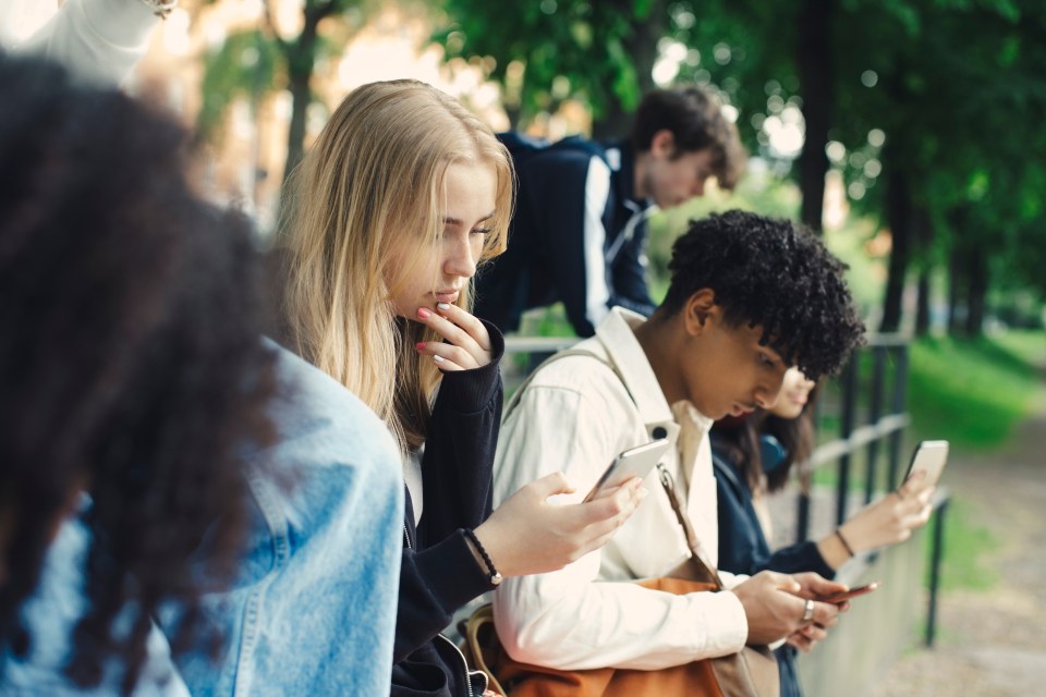 Friends using smartphones in a park.