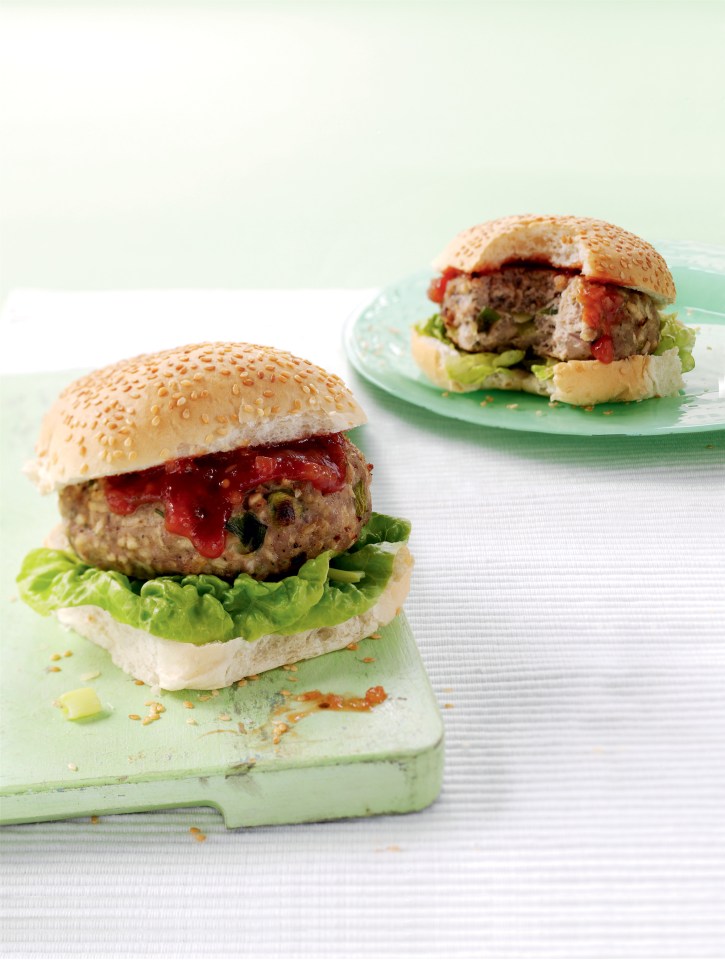 Two burgers on sesame seed buns with lettuce and relish.