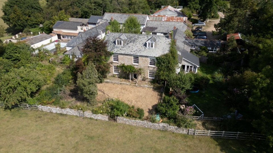 Aerial view of a six-bedroom farmhouse in Devon with a swimming pool and library.