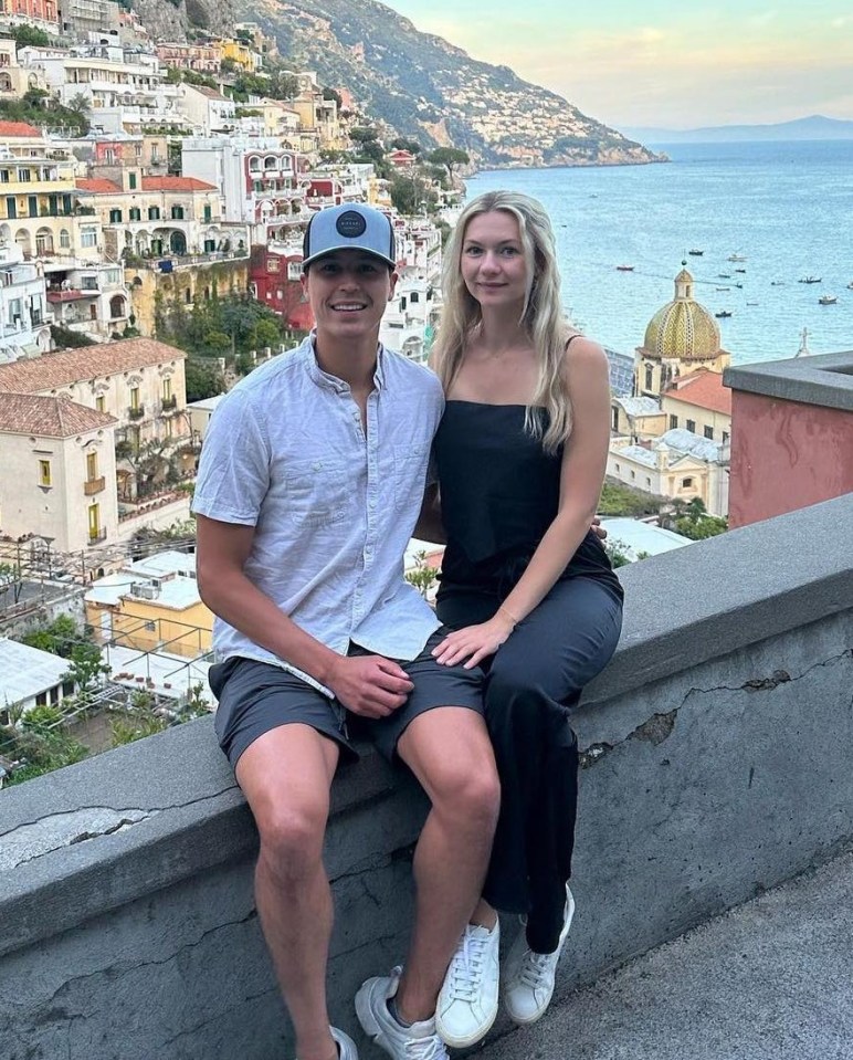 Couple sitting on a wall overlooking Positano, Italy.