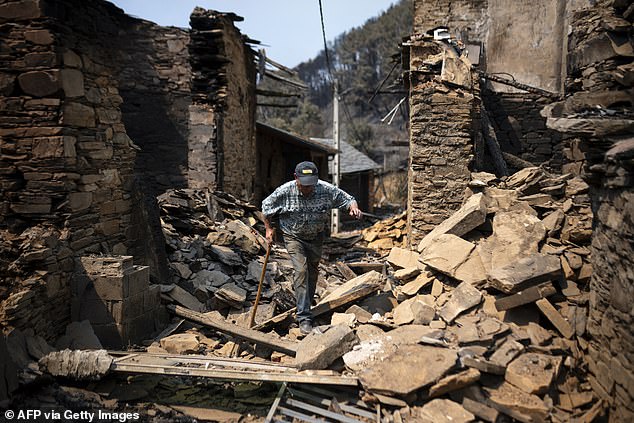 A resident walks among the rubble of houses destroyed by a wildfire in the Spanish northwestern village of San Vicente de Leira, in Ourense province, on August 19, 2025