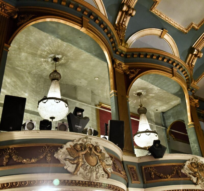 Interior view of the Art Picture House, Wetherspoons, showing ornate gold detailing and two crystal chandeliers.