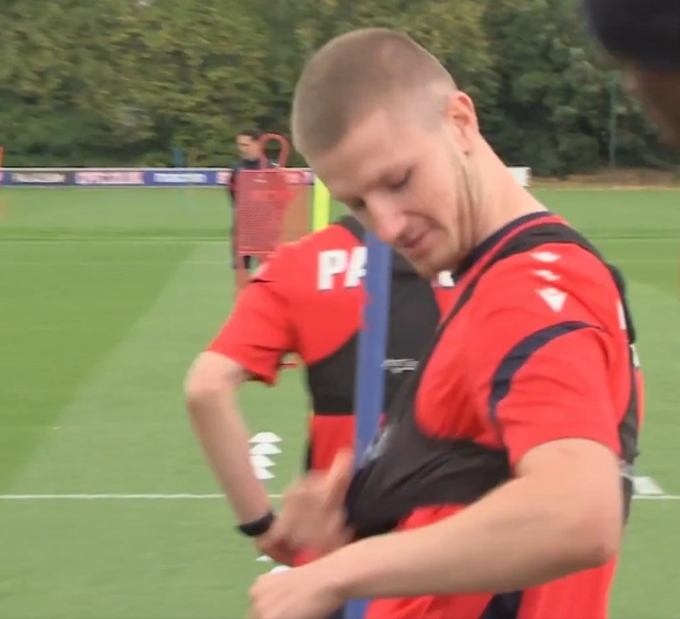 Soccer player adjusting training equipment on field.