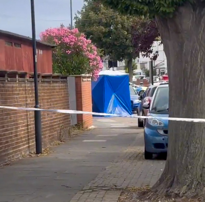 Crime scene in Wembley, UK.  A blue forensic tent is visible behind police tape.