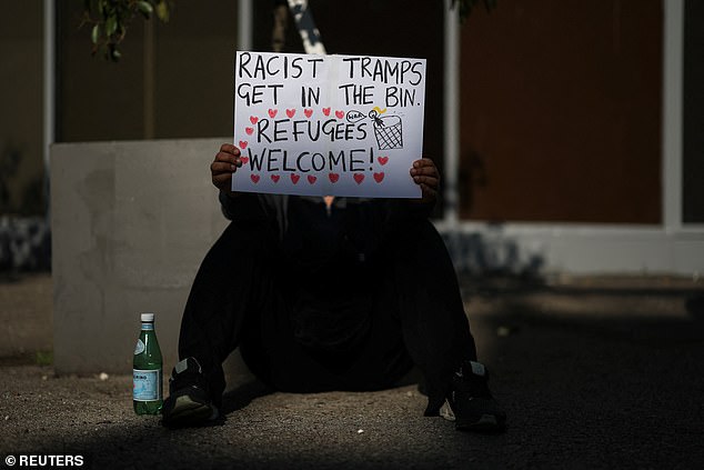 A demonstrator holds an anti-racism sign outside the Thistle City Barbican hotel, in London, on August 8, 2025