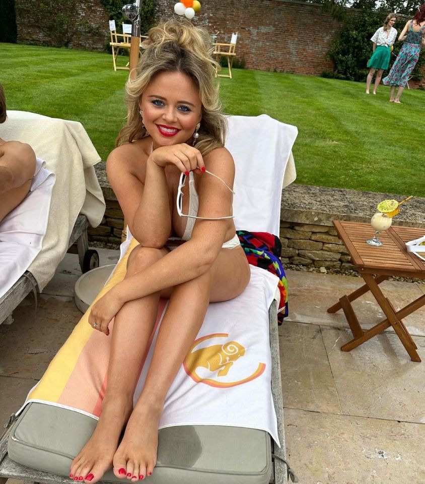 Emily Atack in a bikini on a lounge chair by a pool.