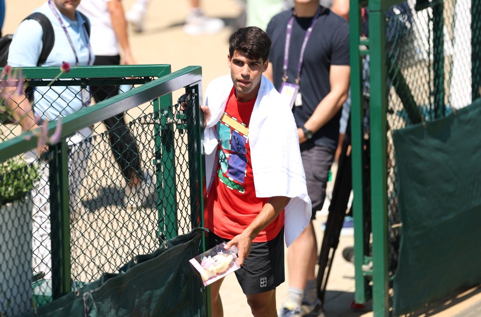 Carlos Alcaraz holding a doll at Wimbledon.