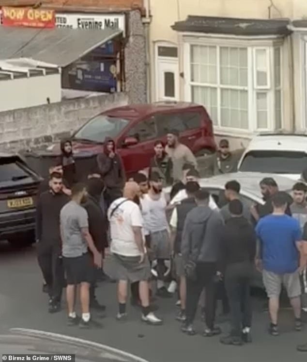 As fighting spilled out into the middle of the suburban thoroughfare a man wearing a grey sweatshirt and black track suit bottoms can be seen holding what appears to be a large knife