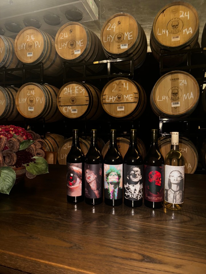 Slate Theory wine bottles in front of wine barrels.