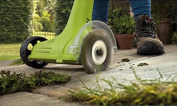 Electric weed sweeper clearing a patio.