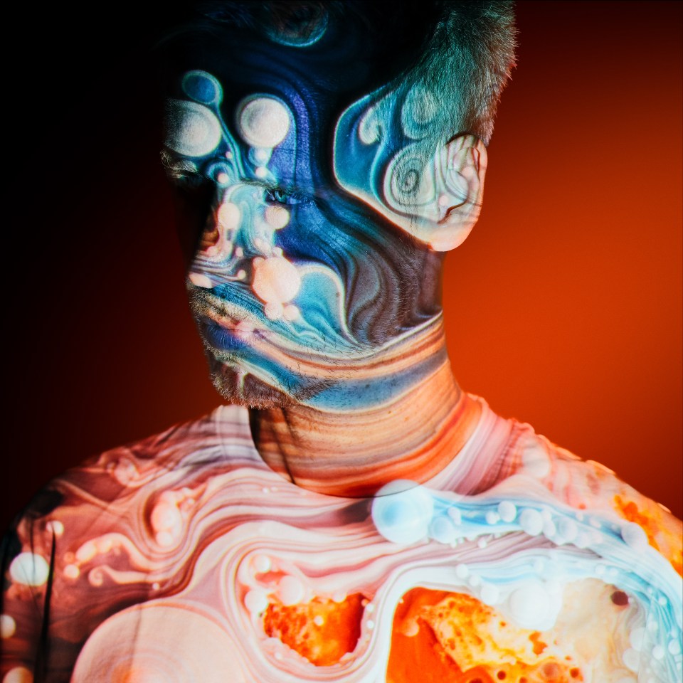 Portrait of Joris Voorn with projected swirling patterns on his face and shirt.