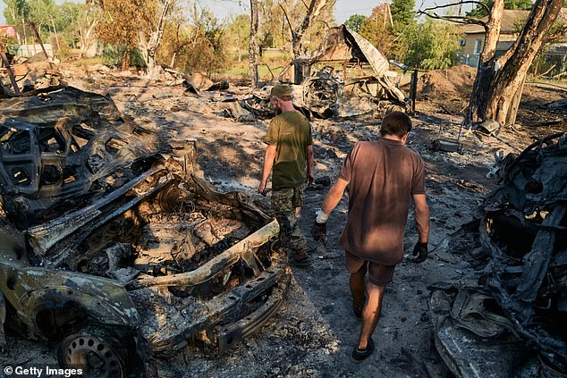 Ukrainian soldiers inspect the site of a Russian Shahed drone strike that destroyed vehicles and residential buildings the previous day on August 20, 2025 in Sloviansk, Ukraine