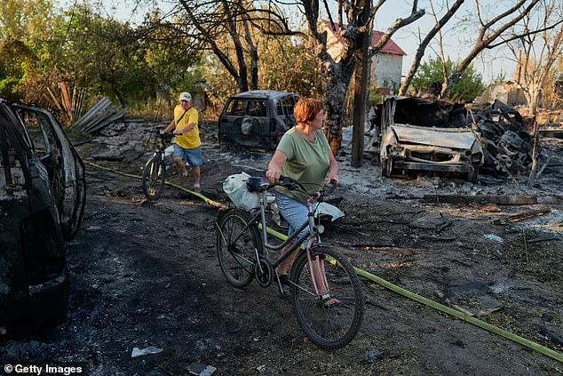 Local residents walk through the site of a Russian Shahed drone strike that destroyed vehicles and residential buildings the previous day on August 20, 2025 in Sloviansk, Ukraine