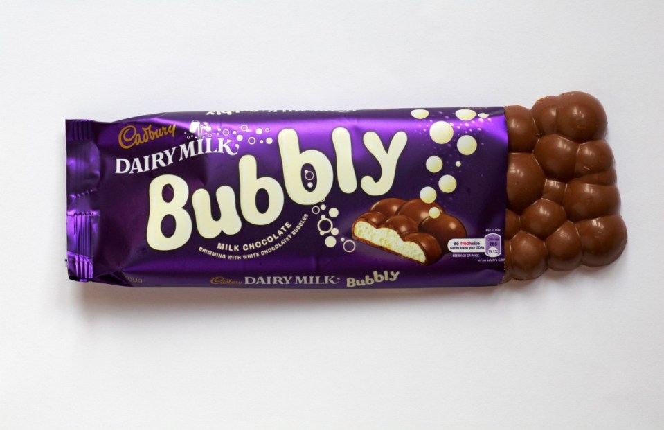 CTMH3J Bar of Cadbury Dairy Milk Bubbly chocolate bar with wrapper undone to show contents isolated on white background