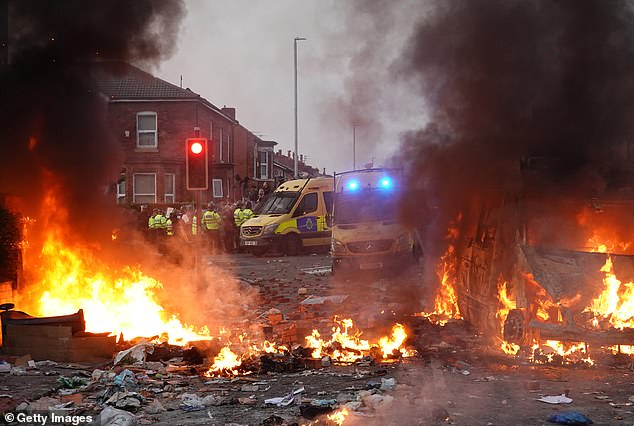Riot police hold back protesters near a burning police vehicle after disorder breaks out in Southport on July 30, 2024
