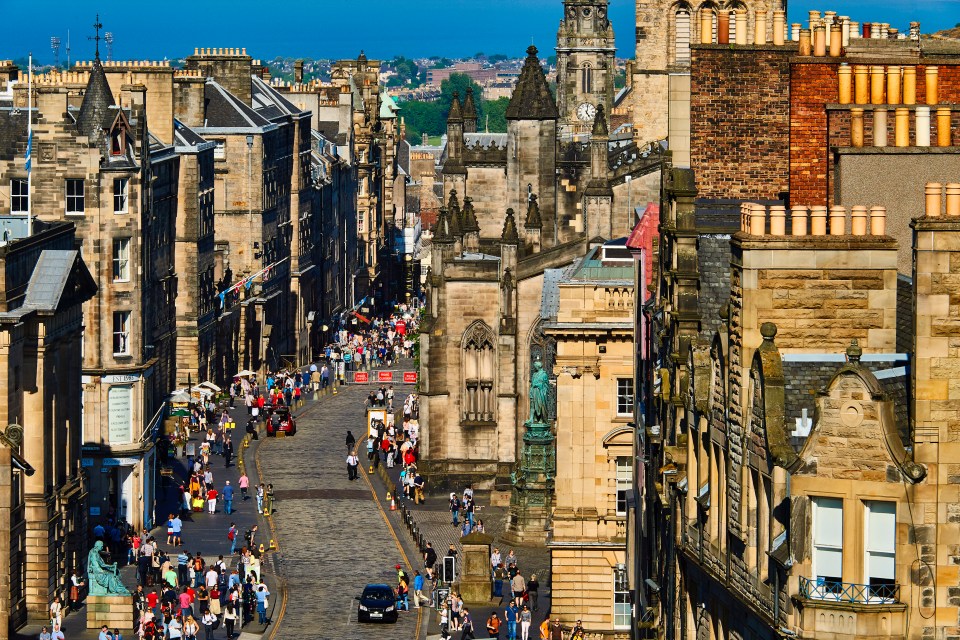 Edinburgh's Royal Mile, with many people walking on a cobblestone street lined with historic buildings.