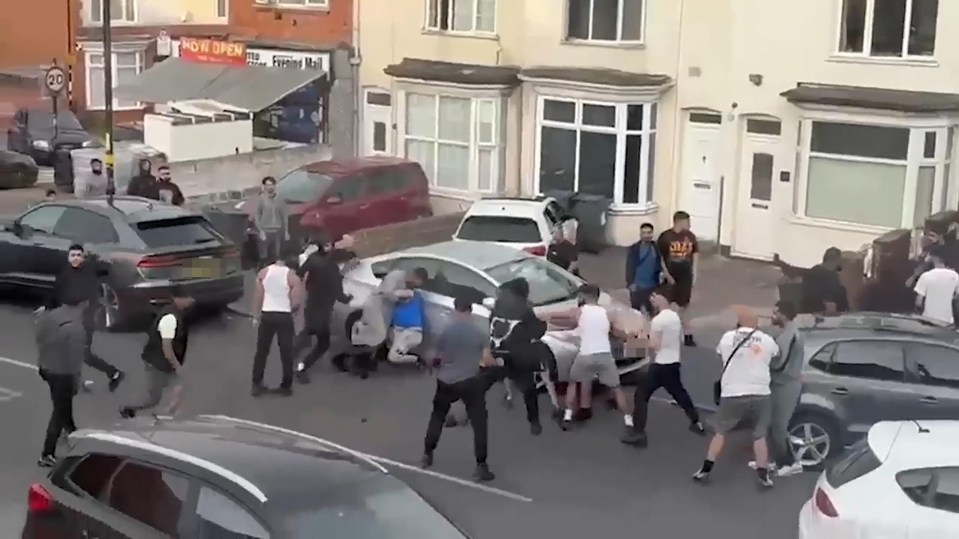 Large group of people fighting in a street.