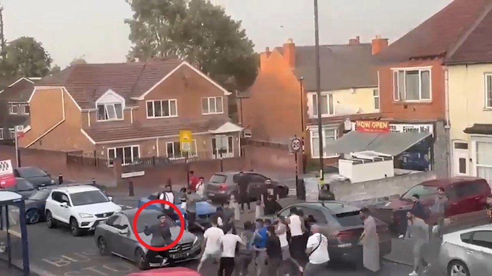 Large group of people fighting in a street.