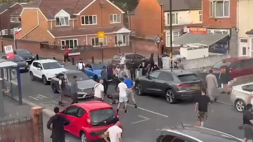 Large group of people fighting in a street.
