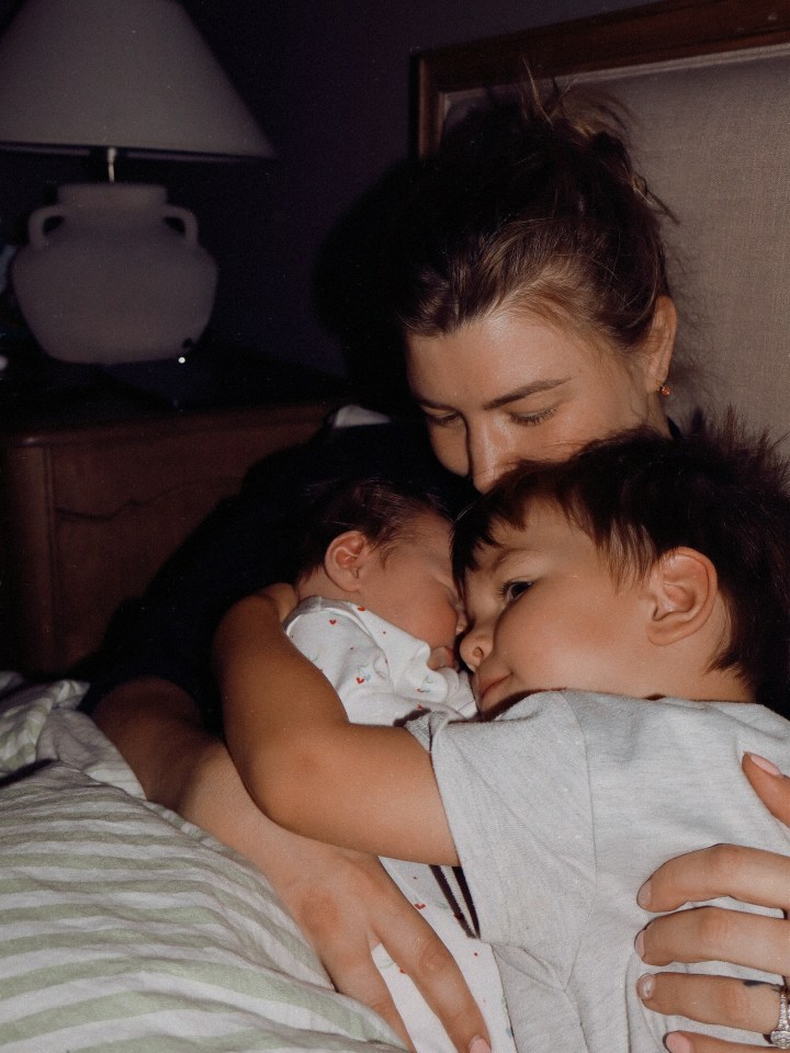 A mother holding her newborn baby and toddler.