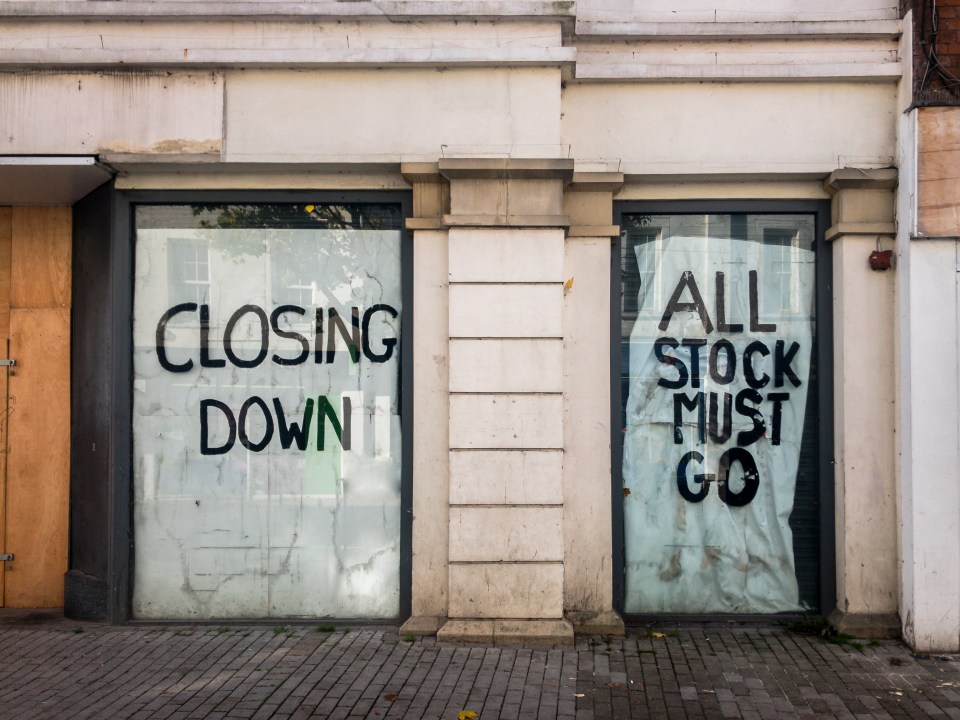 Closed shop windows with signs reading "CLOSING DOWN" and "ALL STOCK MUST GO."