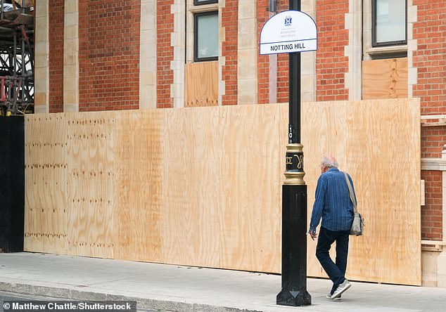 People walk past boarded-up properties in Notting Hill this week before the weekend's carnival