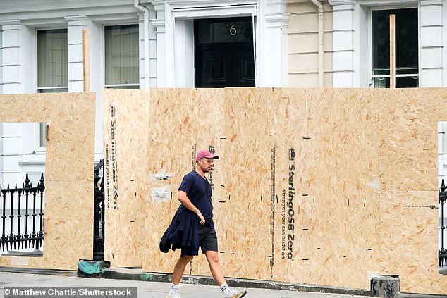 People walk past boarded-up properties in Notting Hill this week before the weekend's carnival
