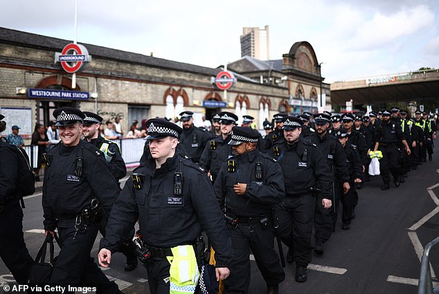 Police march past Westbourne Park Underground Station in west London in August 2024