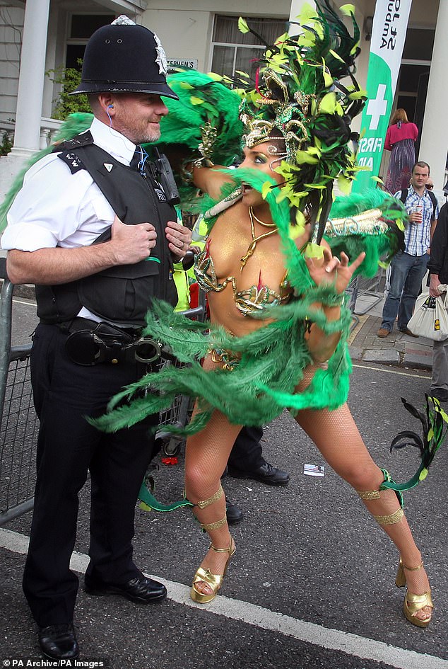 A reveller poses with a police officer during the Notting Hill Carnival in August 2010