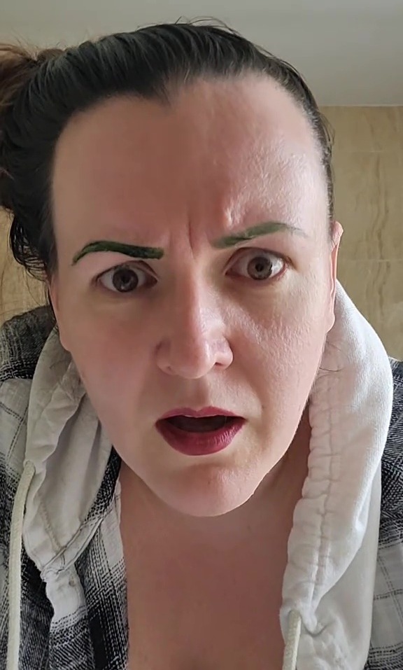 Close-up of a woman with green eyebrows.
