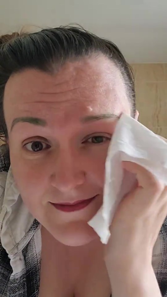 Woman wiping green eyebrow dye.
