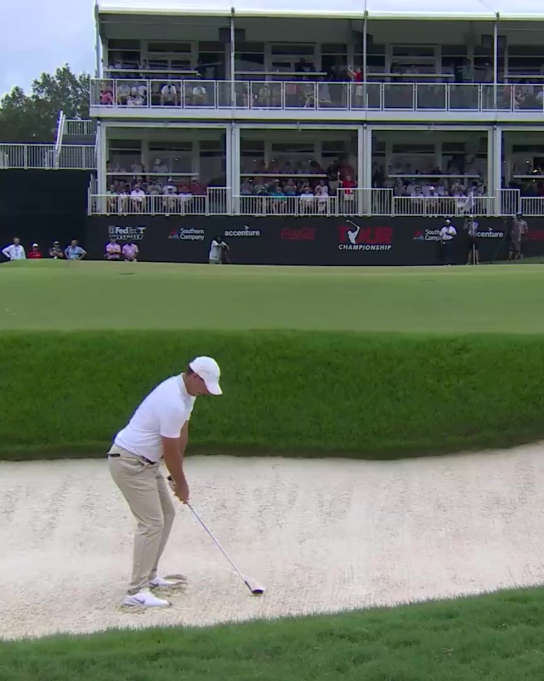 Rory McIlroy hitting a golf shot from a sand trap.