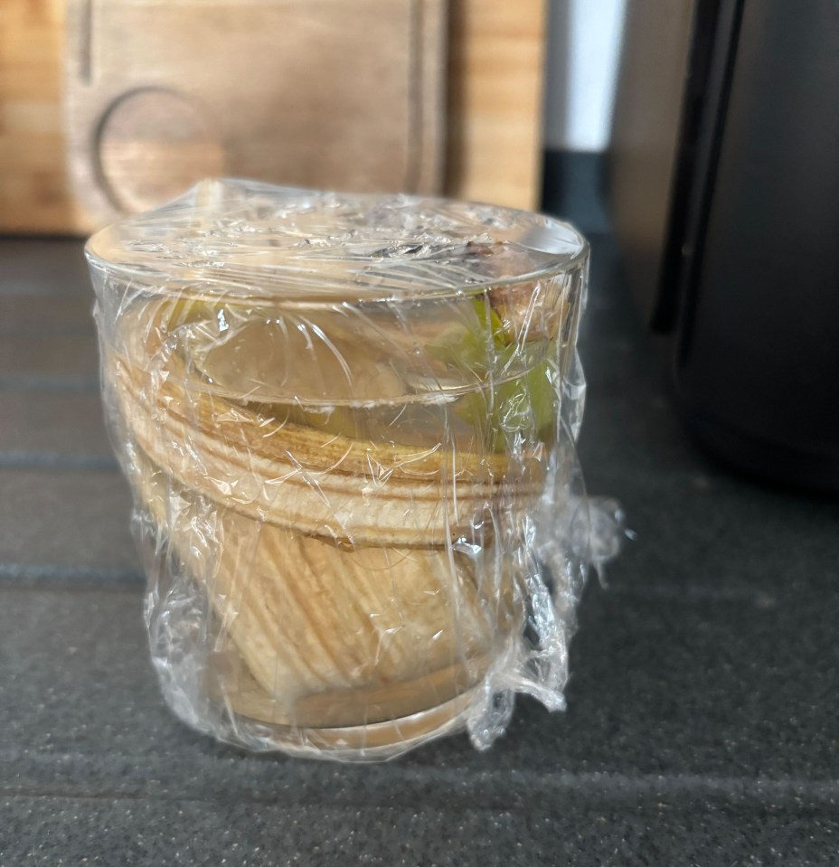Fruit fly trap made from a glass, fruit peels, and plastic wrap.
