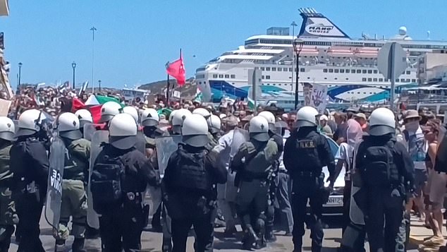 Police in helmets and riot shields watch over the protest against the arrival of Israeli cruise passengers