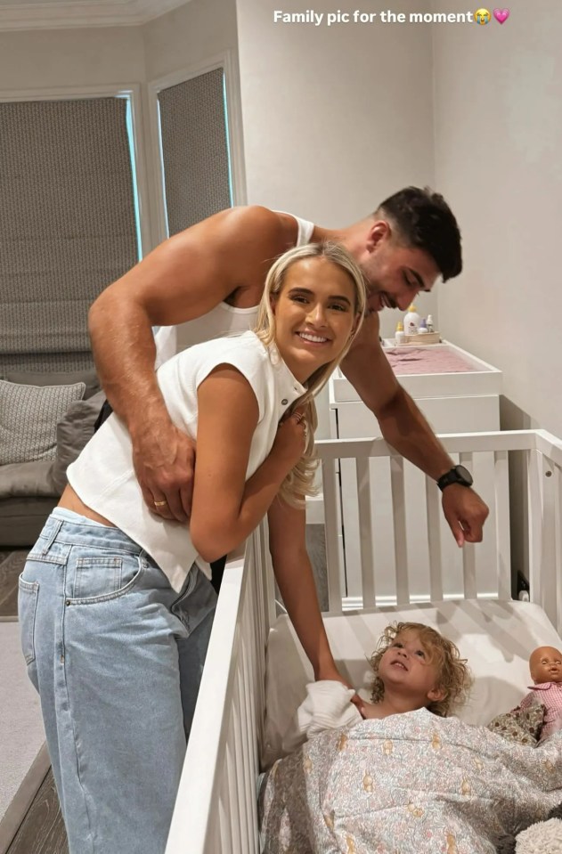 Molly-Mae and Tommy with their baby in a crib.