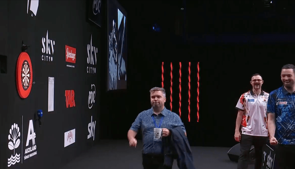 Screenshot of three men at a darts tournament.