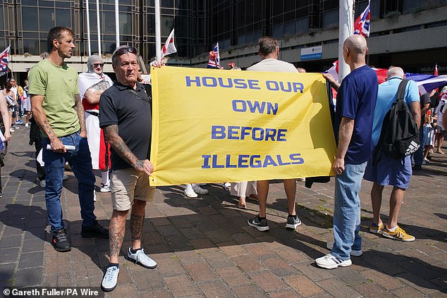 Two other men held a banner reading: 'House our own before illegals'