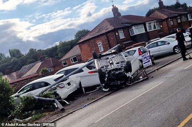 CCTV shows the white car careers along the residential street in Manchester at shocking speed, before hitting the kerb, taking out a lamppost and flipping over onto its roof